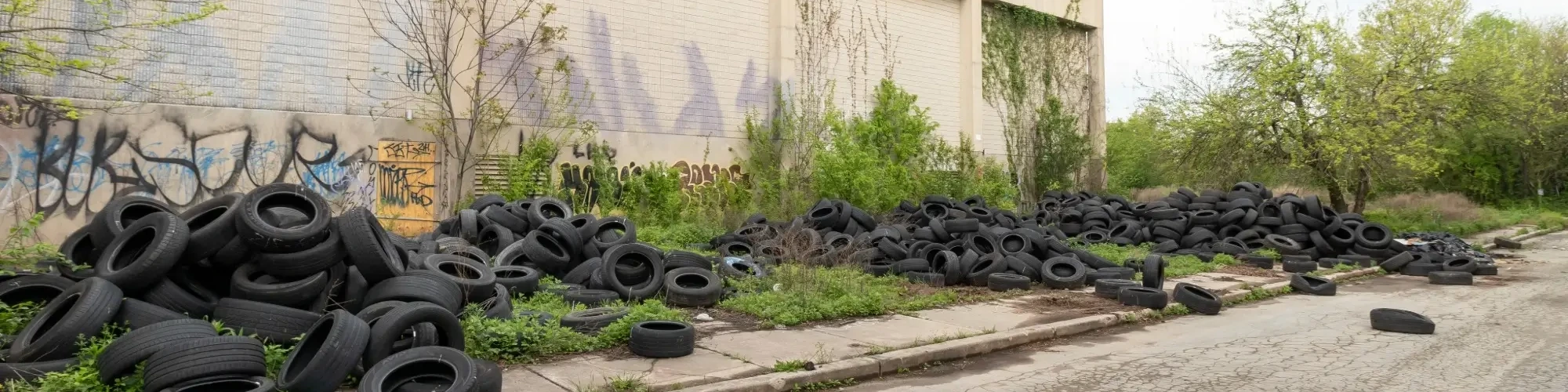 Illegal Dumping of Old Tires and Other Junk Next to an Abandoned Building